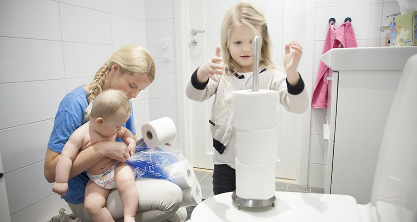 Mother with her kids and sanitary products in the bathroom (photo)