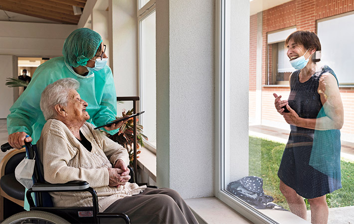 A daughter visits her mother at a retirement home in Italy in 2020. Face masks produced by Essity. (photo)